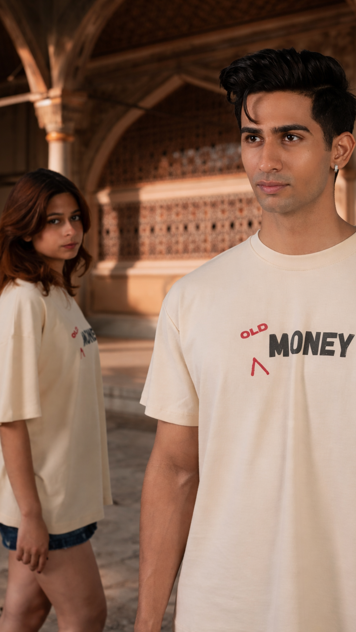 Two people wearing 'Old Money' t-shirts in an outdoor setting.