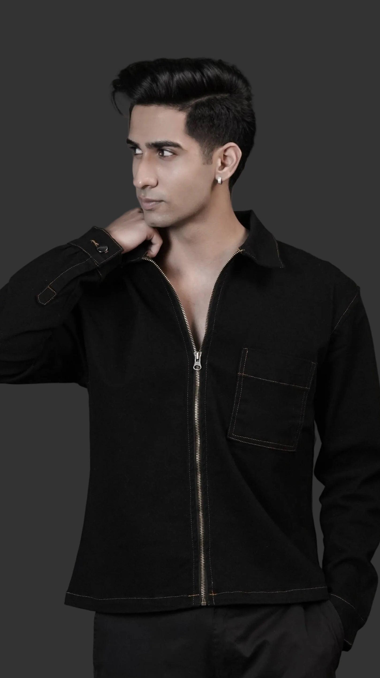Man wearing a black denim jacket against a dark background